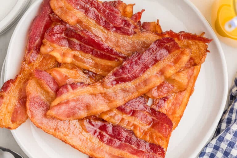 A plate filled with several strips of cooked bacon.