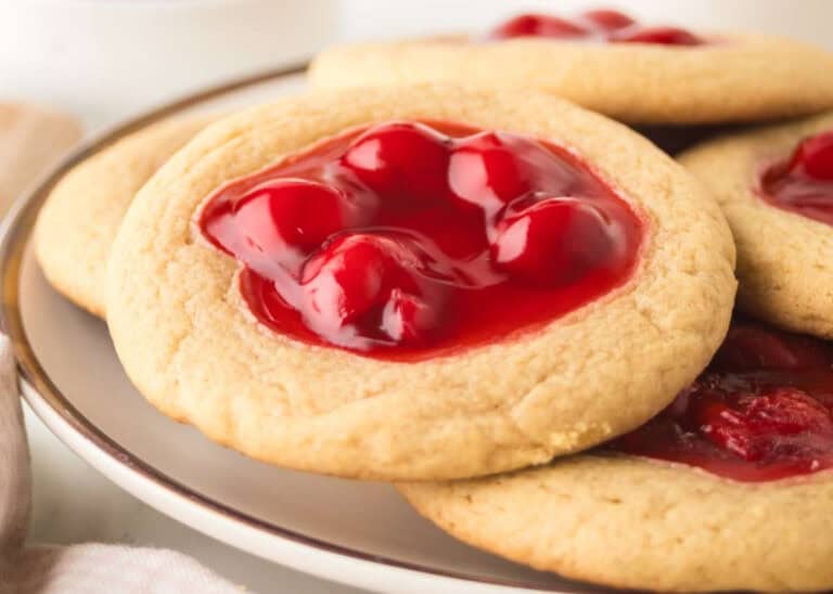 A plate of sugar cookies topped with glossy red cherry pie filling.