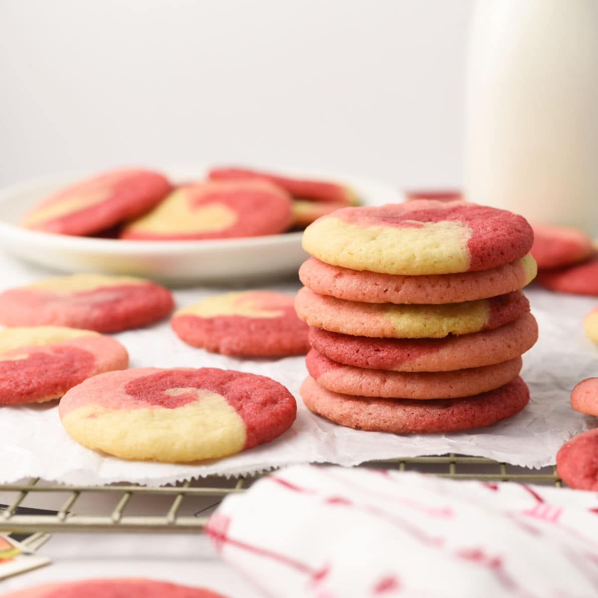 A stack of red, pink and white swirl cookies on a cooling rack.