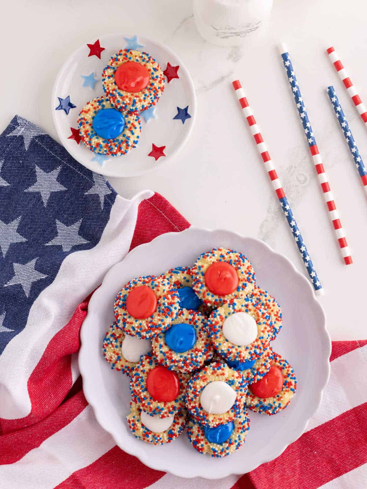 A white plate with red, white and blue thumbprint cookies on a placemat.