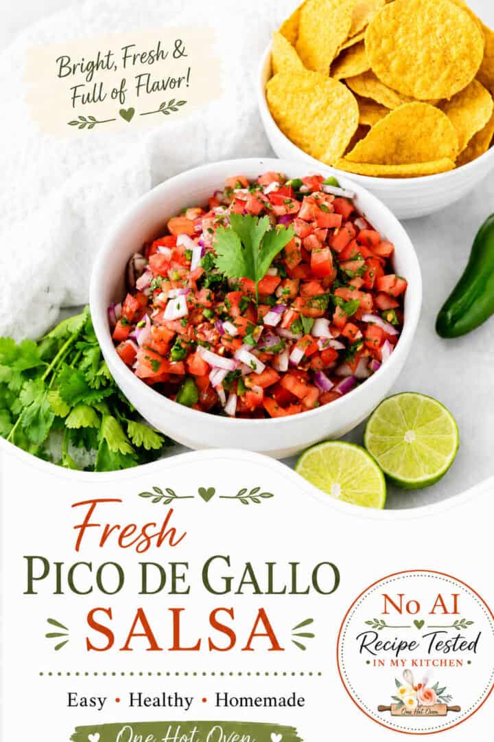 A bowl of pico de gallo salsa garnished with cilantro, surrounded by tortilla chips, lime slices, a jalapeño, and fresh cilantro on a white surface.
