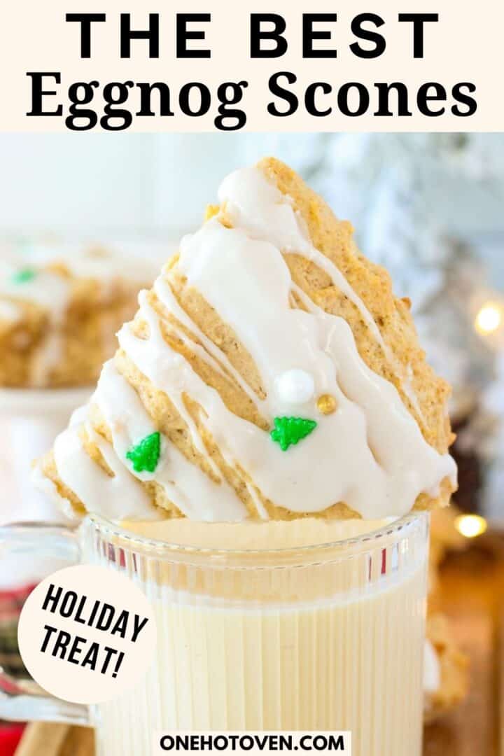 A triangular eggnog scone with white icing and green tree decorations rests on a glass of eggnog. Text reads "The Best Eggnog Scones," "Holiday Treat!" and "onehotoven.com".