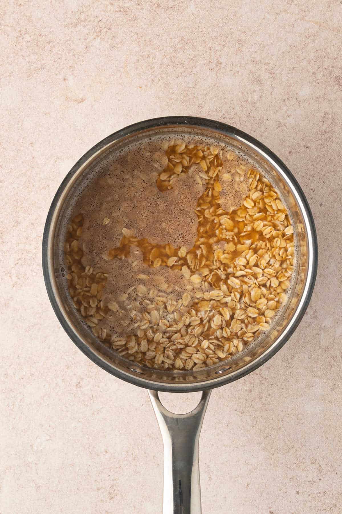 Rolled oats cooking in a saucepan with apple cider.