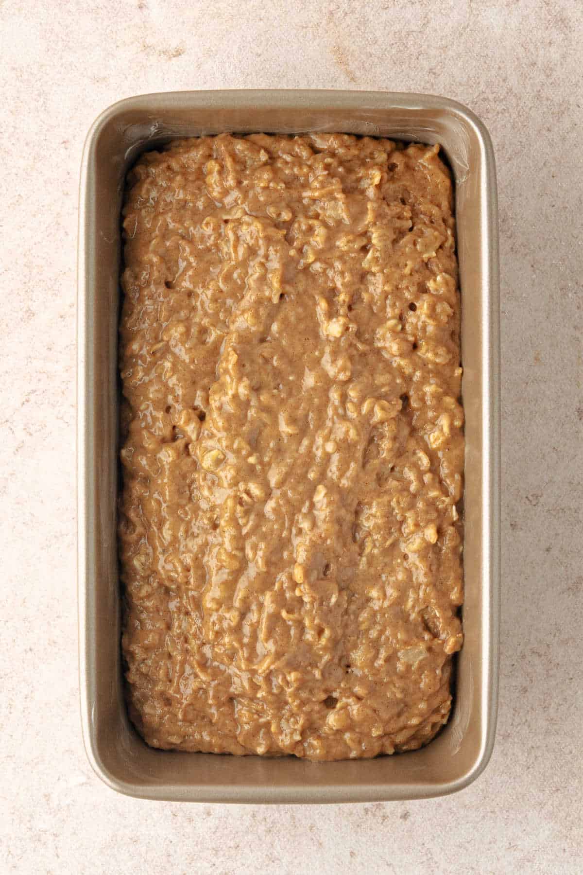 Unbaked apple cider oatmeal bread batter in a metal loaf pan.