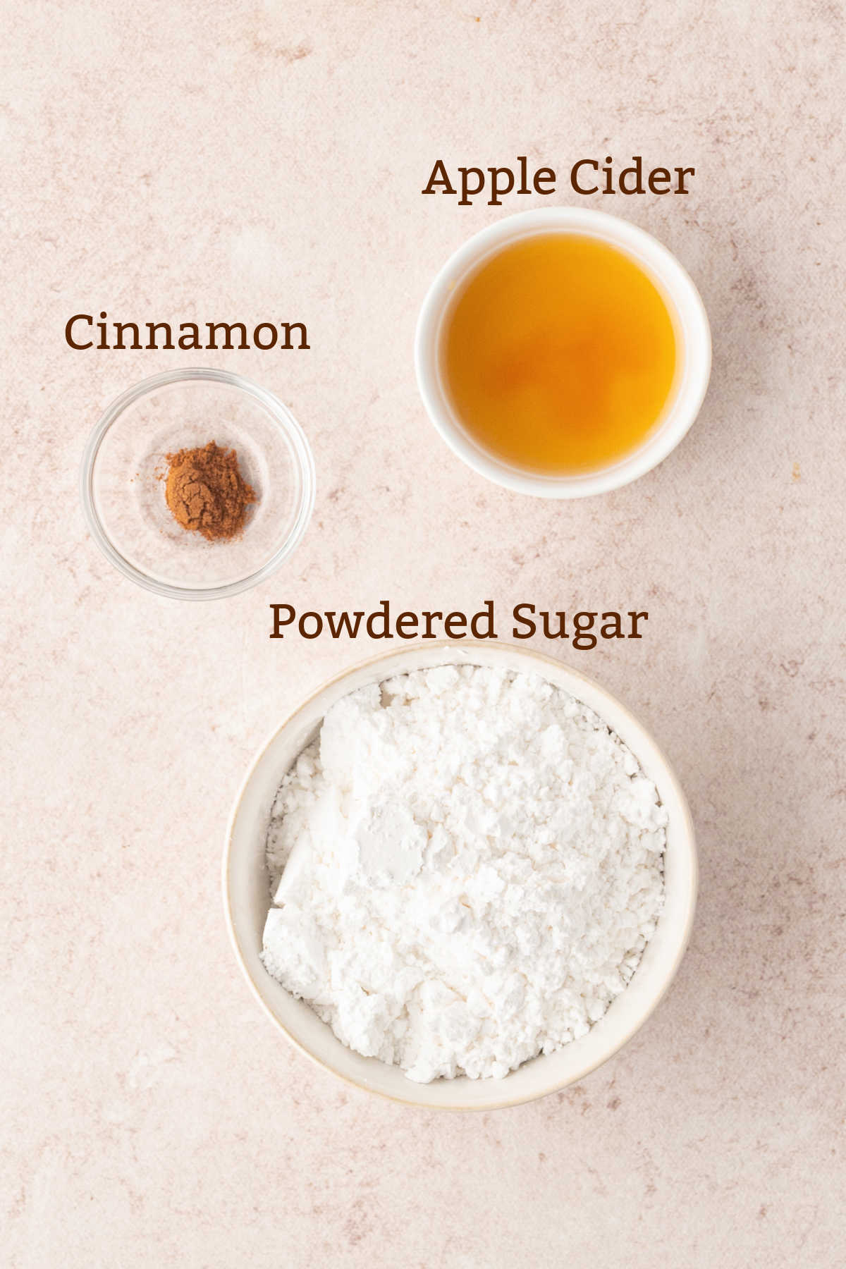 Bowls of apple cider, cinnamon, and powdered sugar, labeled accordingly for a bread glaze.